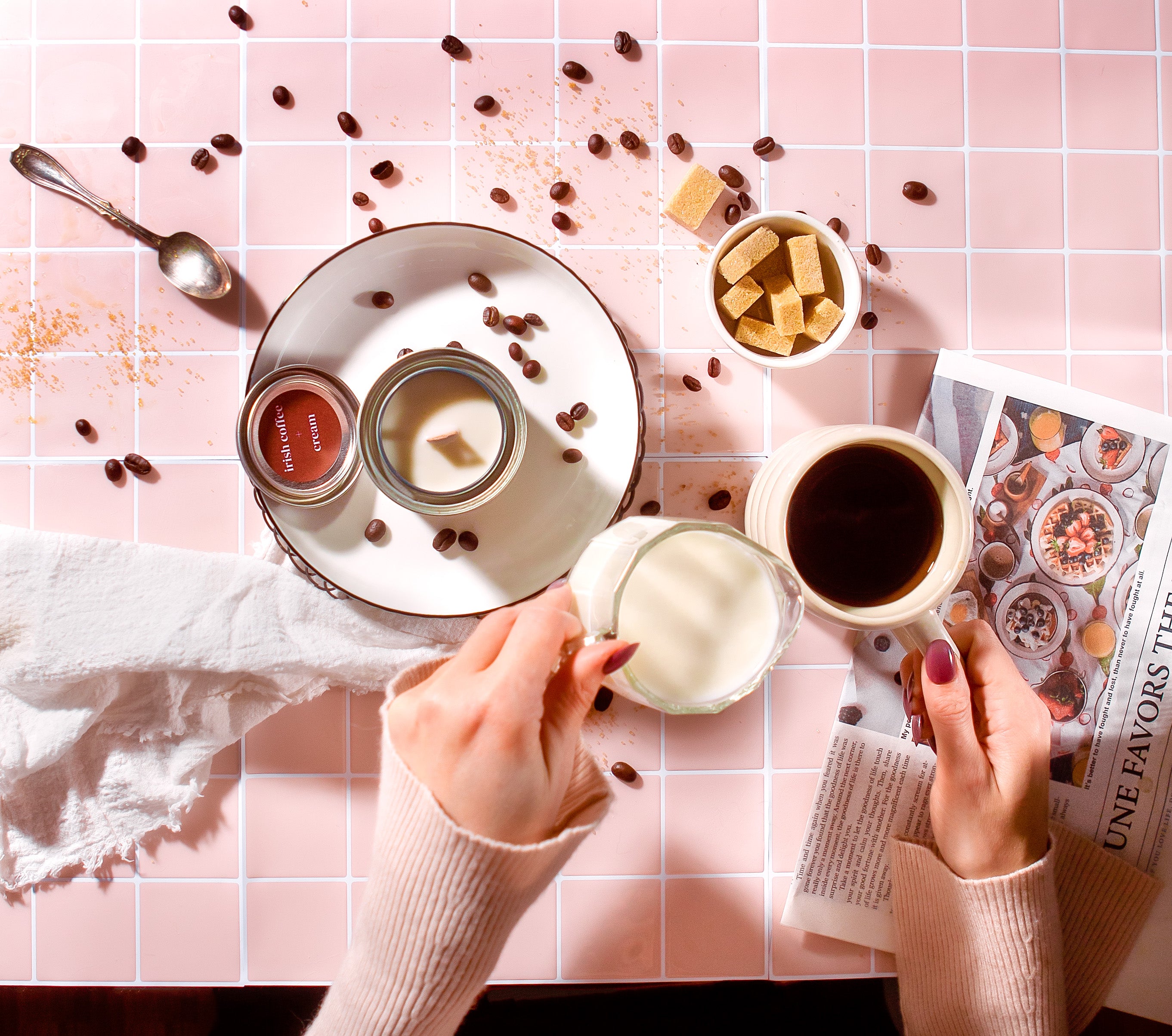 Overhead view of a hand-poured soy candle from a Québec artisanal candle brand, captured during a calm morning coffee ritual with cream being poured and warm, cozy styling.