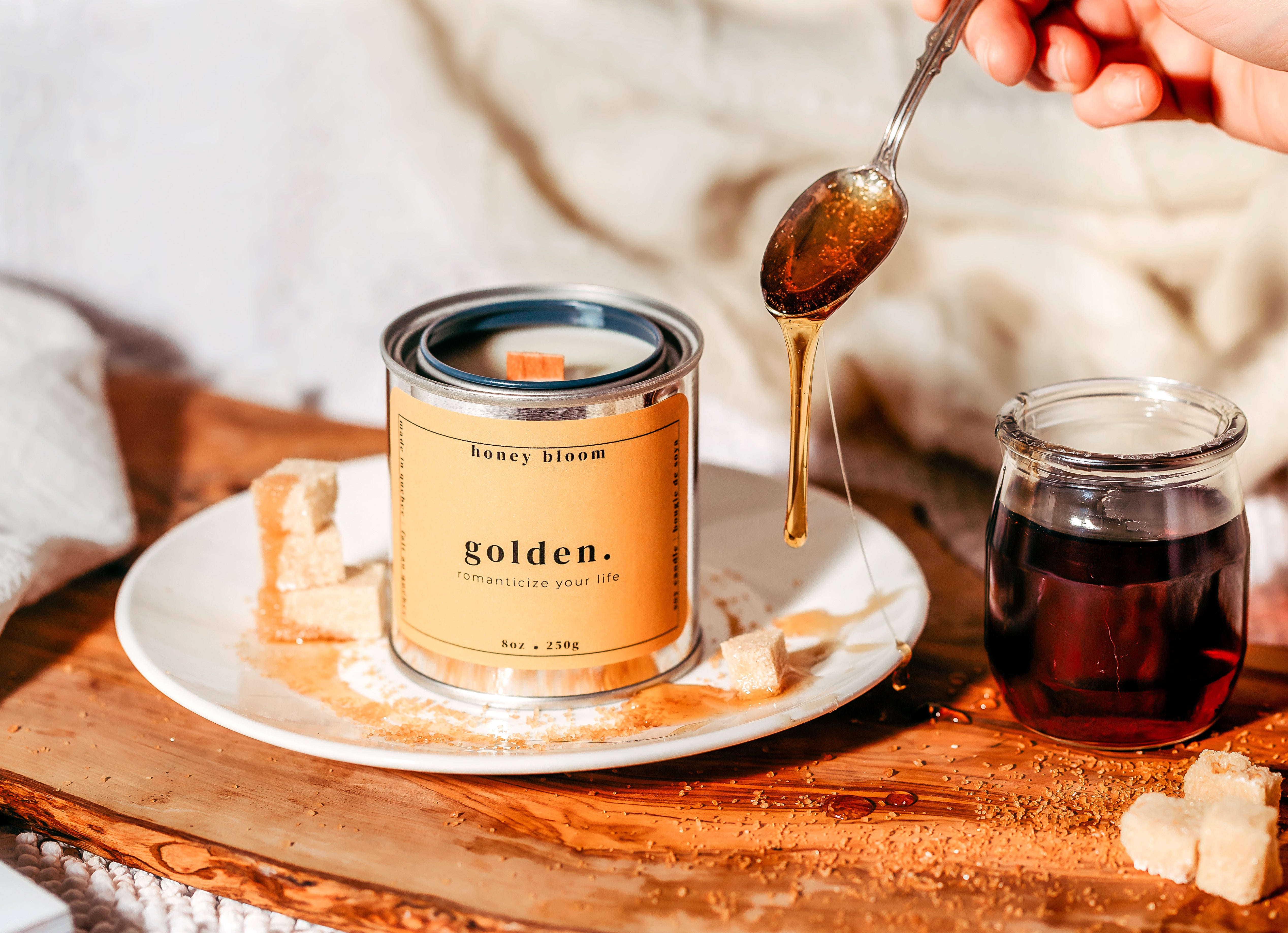 Handmade soy candle “Golden” by Honey Bloom, an artisanal Québec candle brand, styled with dripping honey and warm light.