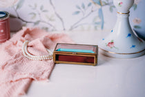 Vintage Via Vermont glass jewelry box with handmade Mexican design on a white countertop.
