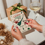 Editable Christmas cocktail party invitation held by hand with festive holiday decorations.