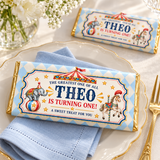Vintage circus chocolate bar favor on a cream plate with a powder blue napkin and gold cutlery.