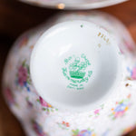 Close-up of a decorative teacup with floral patterns and a visible brand logo.