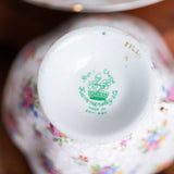 Close-up of a decorative teacup with floral patterns and a visible brand logo.