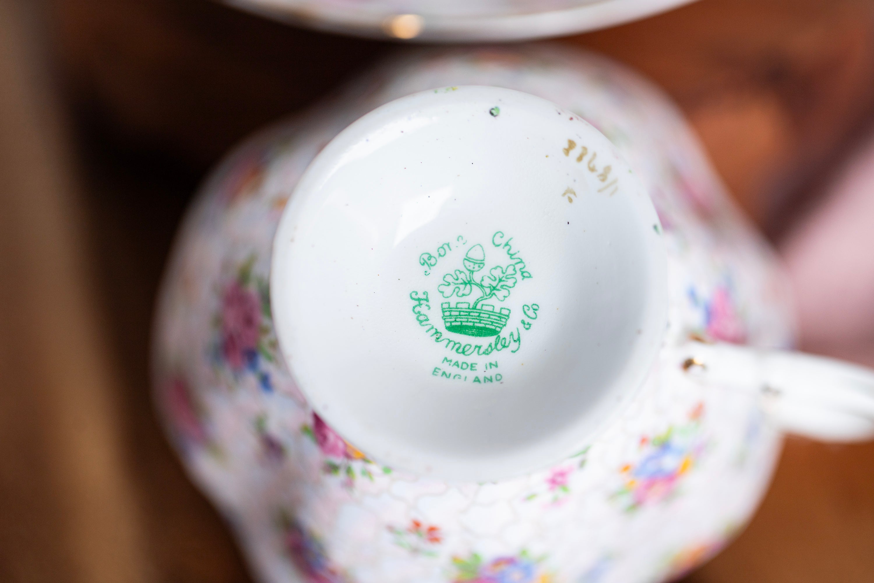 Close-up of a decorative teacup with floral patterns and a visible brand logo.