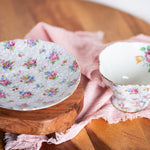 Vintage floral tea cup styled with soft pink fabric and wooden riser