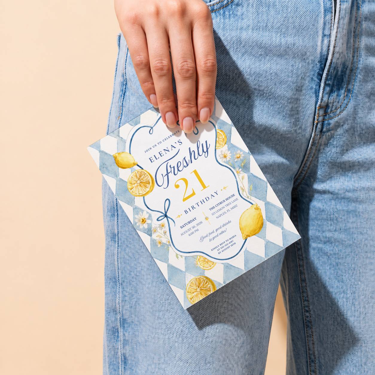 Hand holding a Freshly 21 lemon birthday invitation against a casual denim outfit