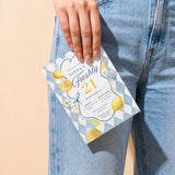 Hand holding a Freshly 21 lemon birthday invitation against a casual denim outfit