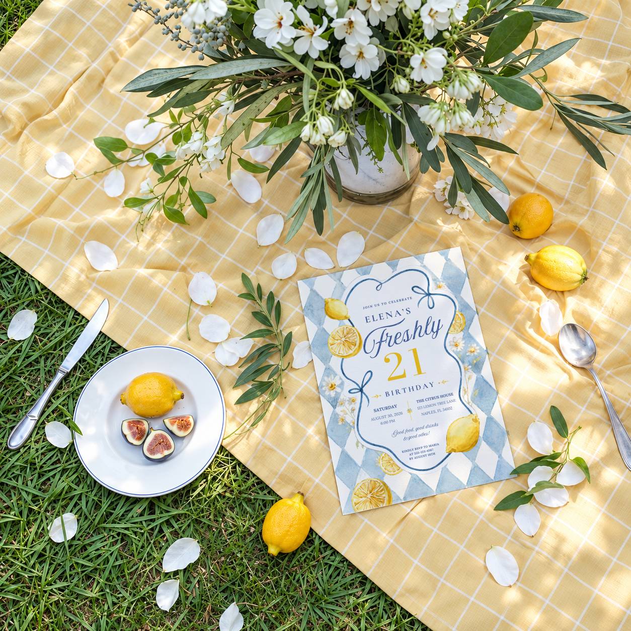 Overhead flat lay of a lemon-themed 21st birthday party invitation with daisies, lemons and yellow gingham