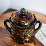 Antique purple carnival glass candy dish with scalloped lid and grape vine details