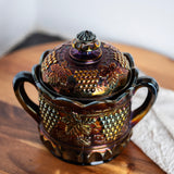 Antique purple carnival glass candy dish with scalloped lid and grape vine details