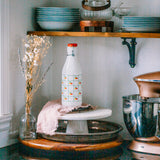 Vintage Italian glass milk bottle 1970s on kitchen tray with apple and pear art deco design.

