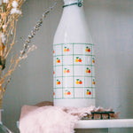 1970s Italian glass milk bottle, apple and pear motif, displayed in kitchen with plants.