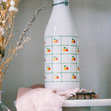 1970s Italian glass milk bottle, apple and pear motif, displayed in kitchen with plants.