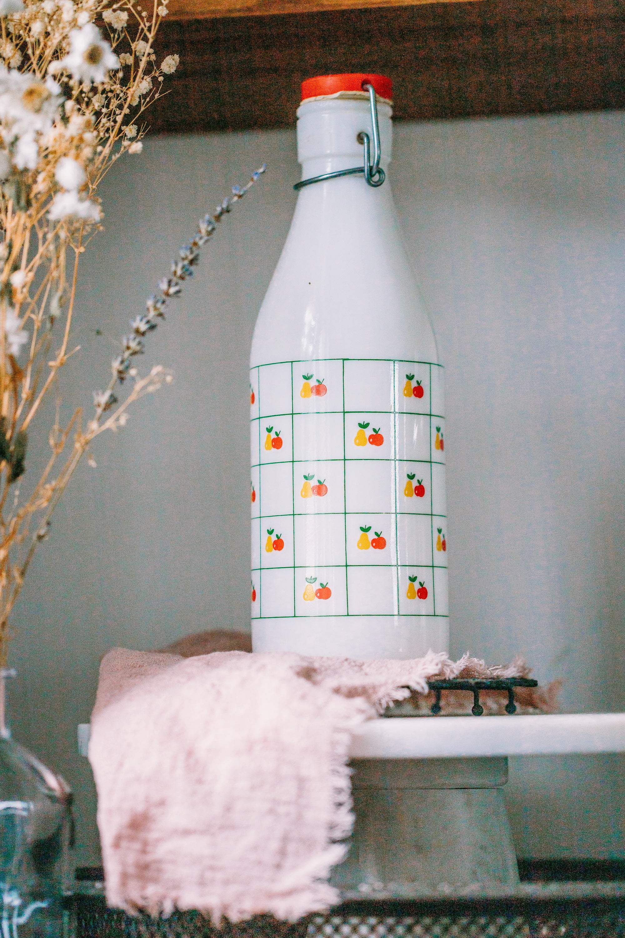 1970s Italian glass milk bottle, apple and pear motif, displayed in kitchen with plants.