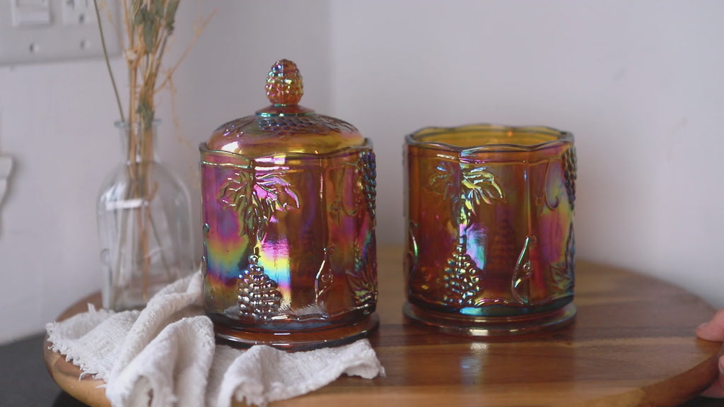 Vintage Indiana Glass amber carnival grape canister set, iridescent lidded jar and open glass container, turning on a tray.
