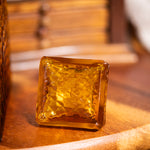 Square amber-colored glass block on a wooden surface