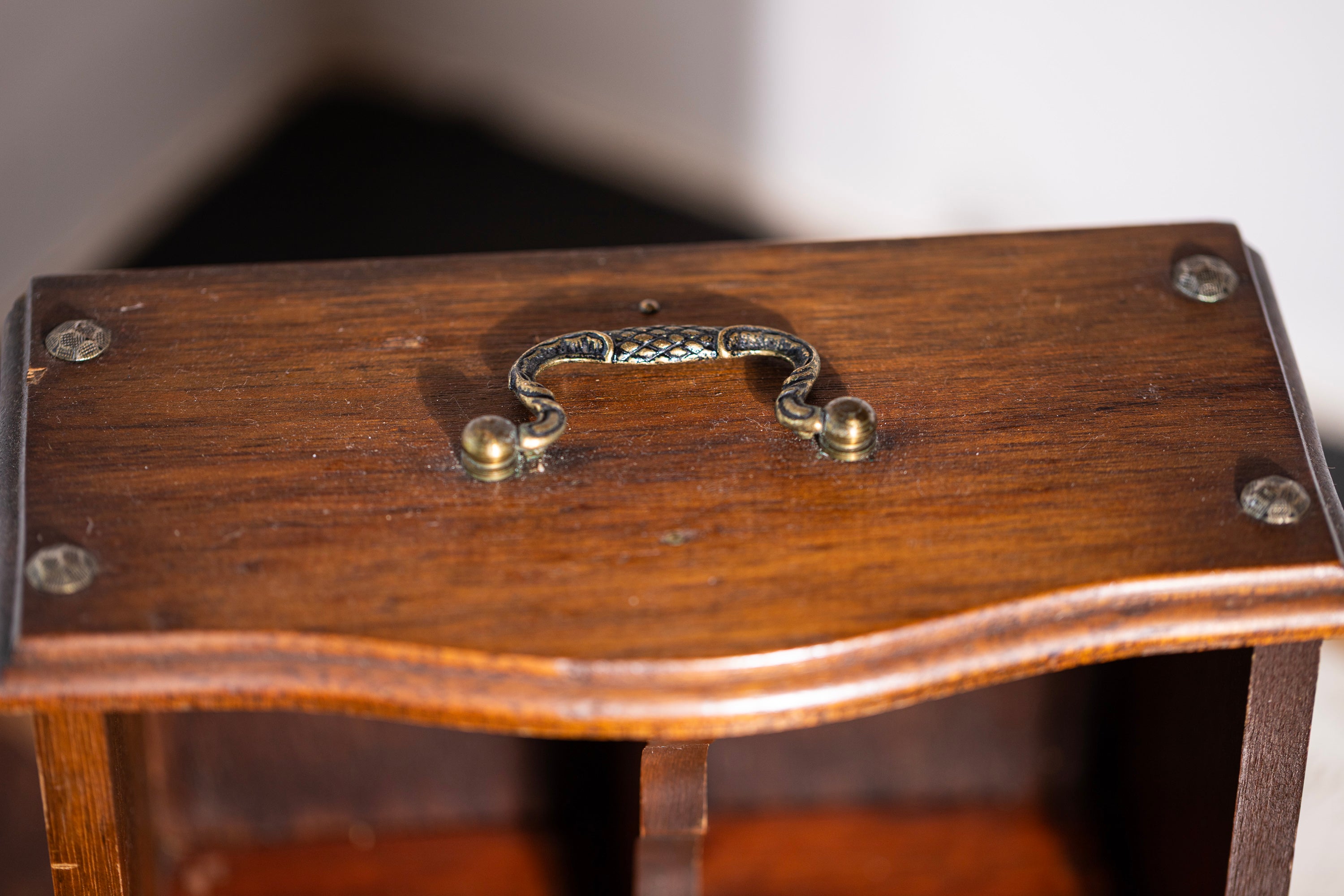 Wooden box with a decorative handle on a plain background