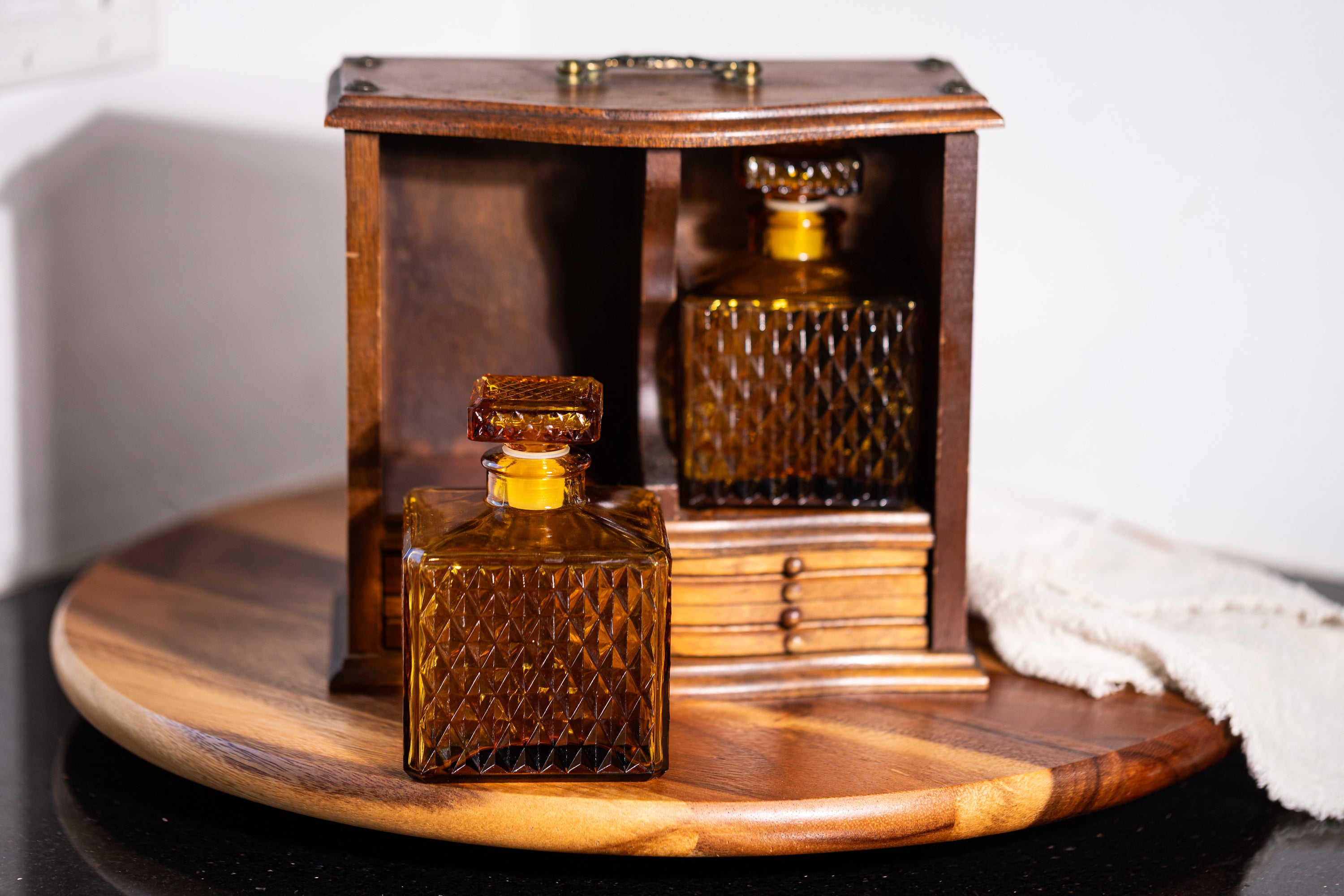 Two amber glass bottles with textured design inside a wooden display case on a wooden surface.