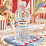 Water bottle with a personalized vintage circus label reading “Vanessa” on a cream plate with a blue napkin and striped straw.