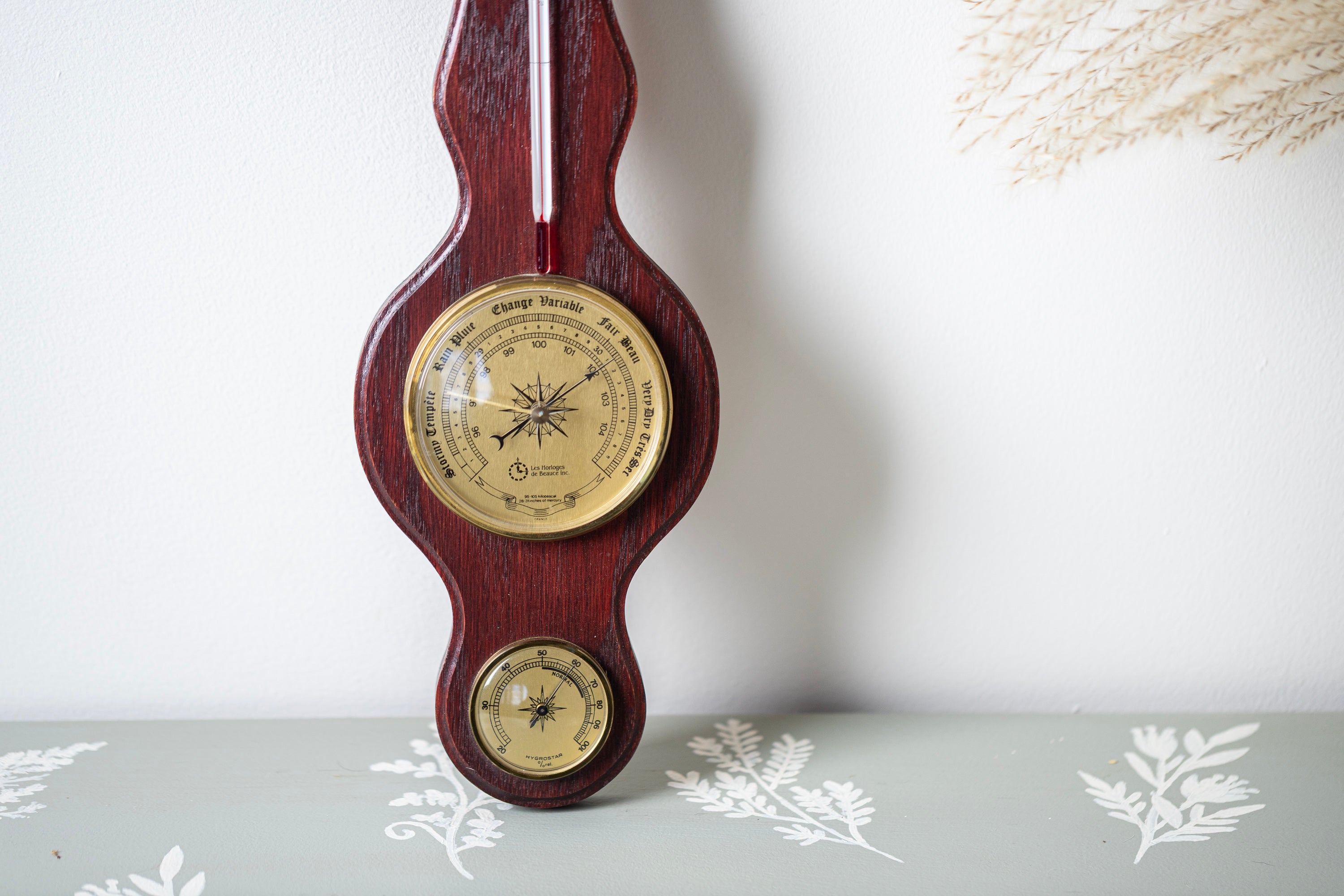 Retro wooden wall weather station with brass tone instruments and reddish wood finish