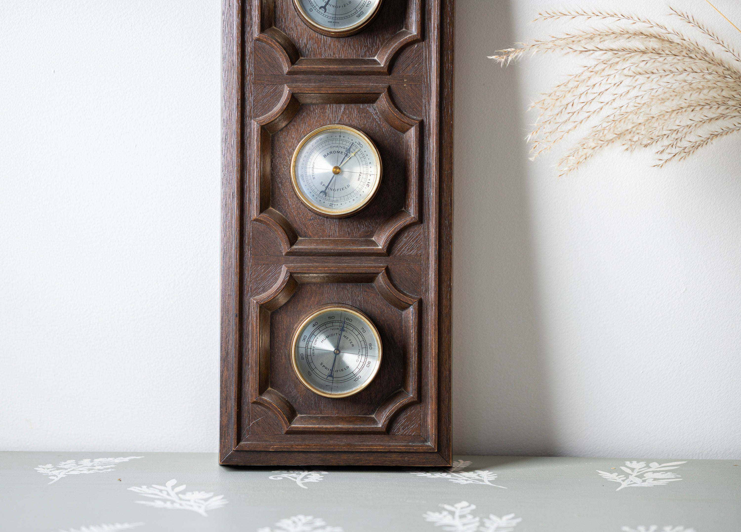 Wooden wall-mounted thermometer with decorative design on a light background