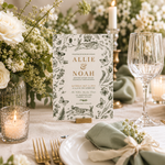 A wedding invitation card displayed on a small wooden stand on a decorated table setting. The card features black botanical illustrations of flowers, leaves, and butterflies on a white background, with the names 'ALLIE & NOAH' in elegant gold lettering.