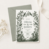 Ivory woodland wedding invitation with green forest animals and botanical details, arranged over a sage-green envelope.